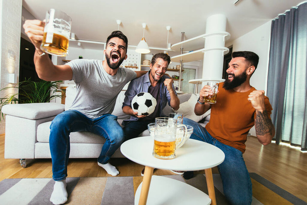 Ενθουσιασμένοι φίλοι βλέποντας ποδόσφαιρο και κρατώντας μπύρες και ποπ κορν - Φωτογραφία, εικόνα