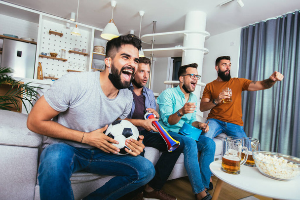 Amigos entusiasmados assistindo jogo de futebol e segurando cerveja e pipocas - Foto, Imagem