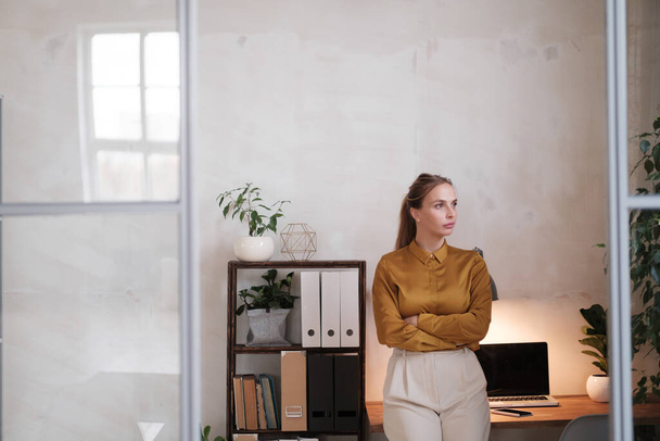 Φωτογραφία της όμορφης γυναίκας εργαζόμενη επιχειρηματίας ντυμένη με επίσημη ένδυση κοιτάζοντας την κάμερα ενώ εργάζεται και κάθεται στο γραφείο απομονωμένη σε λευκό φόντο - Φωτογραφία, εικόνα