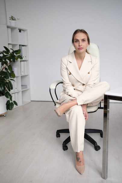 Photo of beauty female worker businesswoman dressed in formal wear looking at camera while working and sitting at desk in office isolated over white background - Foto, immagini