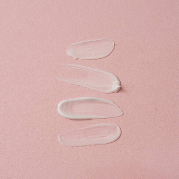 Kosmetický výrobek. Bílé kosmetické krémové šmouhy, šmouha izolované na růžovém pozadí - Fotografie, Obrázek