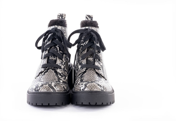Par de botas de suela Lug con patrón de piel de serpiente y cordones de zapatos aislados en blanco - Foto, imagen
