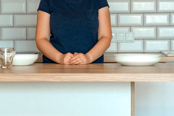  γυναίκα στέκεται κοντά στο τραπέζι στην κουζίνα στο σπίτι.woman στο σπίτι με φόντο κουζίνα. - Φωτογραφία, εικόνα