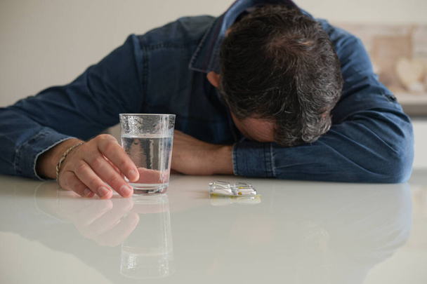 caucasian man taking medicine for a migraine at home - Photo, image