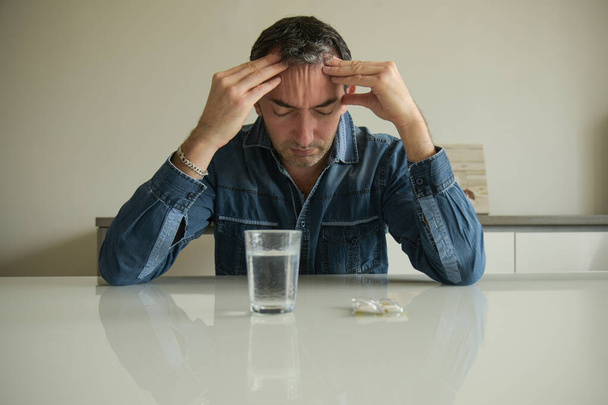 caucasian man taking medicine for a migraine at home - Fotó, kép