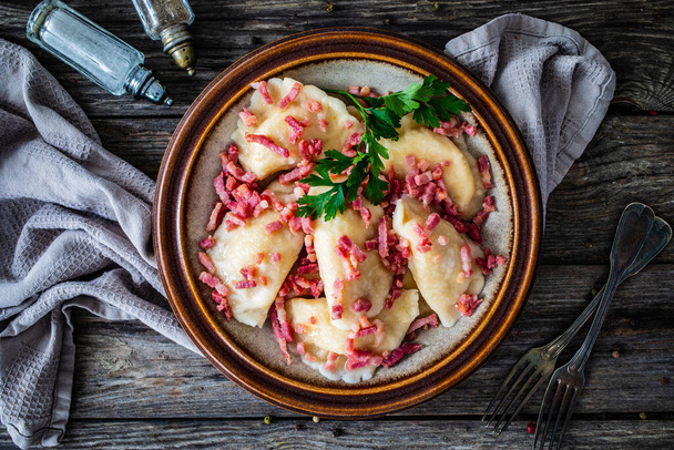 Dumplings - cheese noodles with onion and bacon on wooden background  - Photo, image