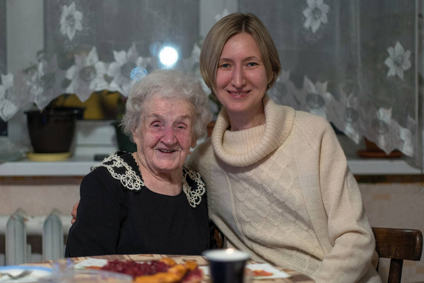 Bir kadın yaşlı büyükannesiyle birlikte sandalyede poz veriyor.. - Fotoğraf, Görsel