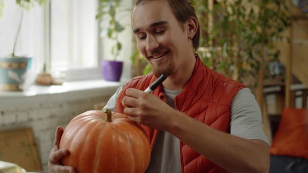 A young man is drawing neatly on the pumpkin - Photo, Image
