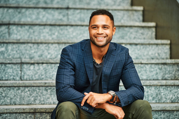 Outdoor urban portrait of African American male model sitting on stairs - 写真・画像