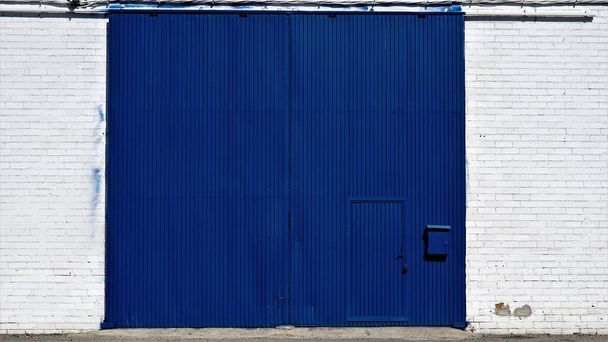 puerta industrial azul en fachada blanca - Foto, Imagen