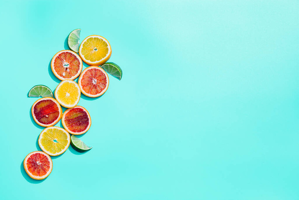 Bright slices citrus fruits, grapefruit, red orange, lemon, lime on pastel turquoise background. - Foto, afbeelding