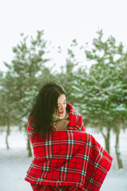 Young cute girl with durk hair in red scarf has fun in snowy weather in winter in the park. Life style  - Fotografie, Obrázek