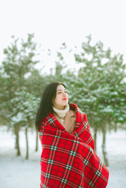 Young cute girl with durk hair in red scarf has fun in snowy weather in winter in the park. Life style  - Foto, Imagem