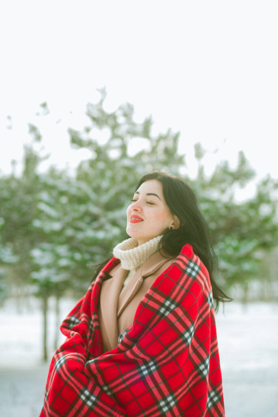 Young cute girl with durk hair in red scarf has fun in snowy weather in winter in the park. Life style  - Photo, image