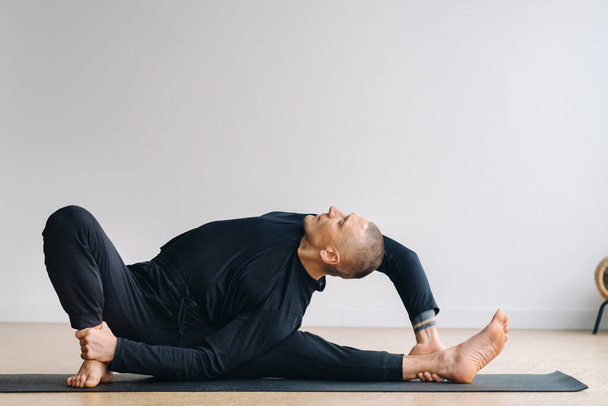 A man in black sportswear is doing Yoga, stretching in the gym. - Fotó, kép