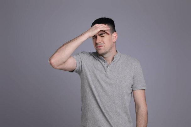 Young man suffering from headache on grey background. Cold symptoms - Zdjęcie, obraz