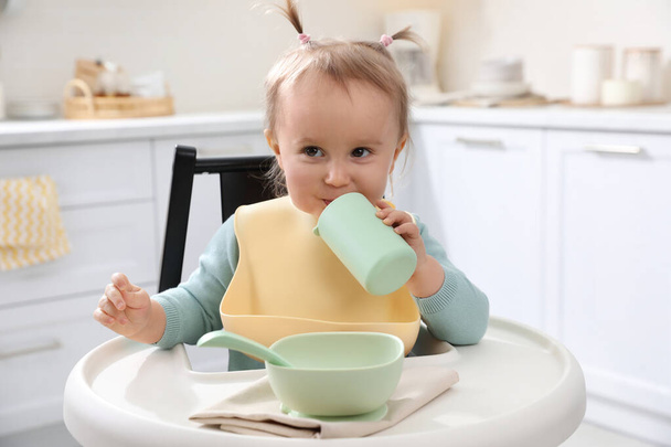 Cute little baby drinking from bottle in kitchen - Fotó, kép