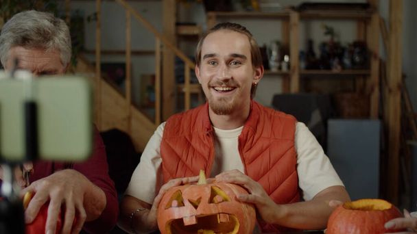 A young man with his parents talking to the camera how to make halloween pumpkins - Photo, Image