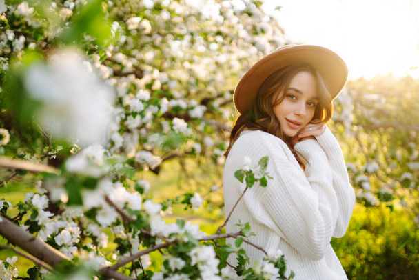Young woman enjoying scent in blooming spring garden. The concept of relax, travel, freedom and spring vacation. Fashion style - Φωτογραφία, εικόνα