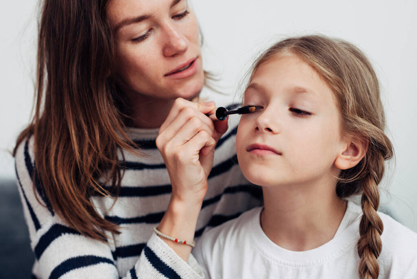 Moeder zet mascara op haar dochters wimpers - Foto, afbeelding