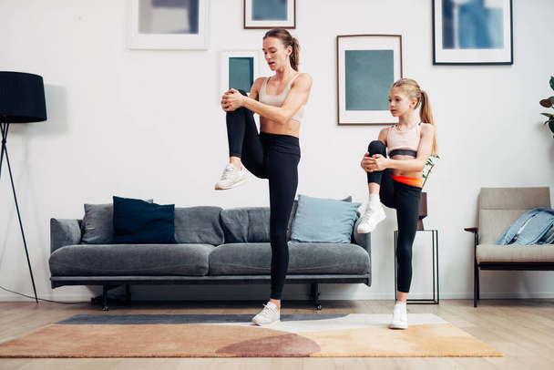 Mother and daughter working out at home, doing stretching exercises - Photo, image