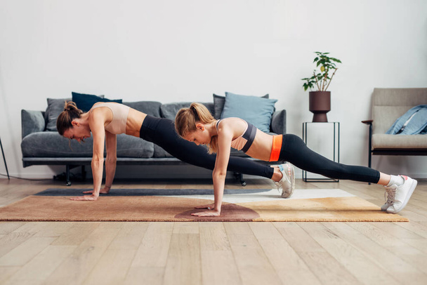 Mother and daughter working out at home, doing push-ups - Photo, Image