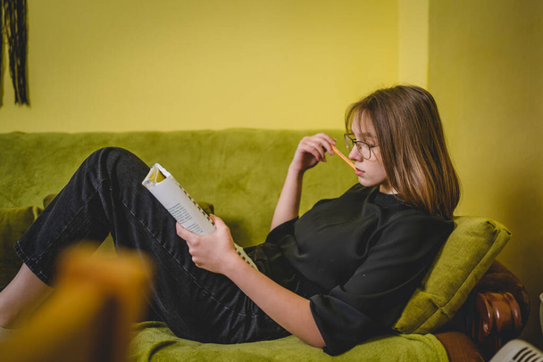 Eine junge kaukasische Studentin studiert, während sie zu Hause in ihrem Bett liegt - Foto, Bild