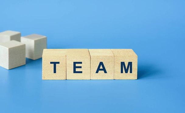 チームのビジネスコンセプト、青い背景にテキストチームと木製のキューブブロック。優秀な人材とチームが成功への鍵です - 写真・画像