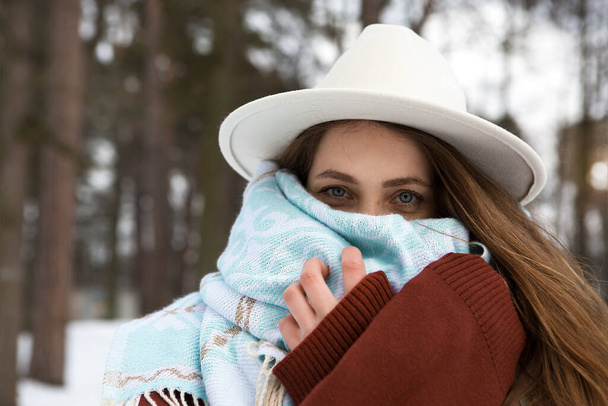 Young beautiful woman covers herself with a scarf from the cold. - Photo, Image