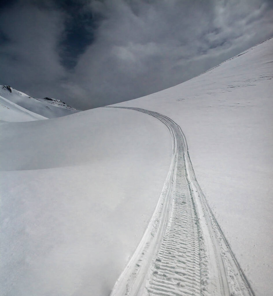  Sentier de pistes de ski et de motoneige sur neige blanche sur col de montagne. Trajectoire de piste de motoneige sur neige pure et profonde en montagne.  - Photo, image