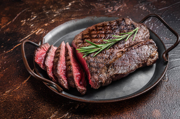 Grilled Medium Rare top sirloin beef steak or rump steak on a steel tray. Dark background. Top view - Photo, image