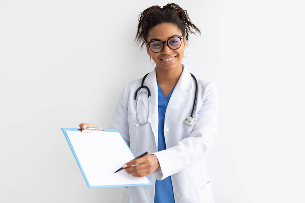Portrait of black doctor looking at camera showing clipboard - Photo, Image