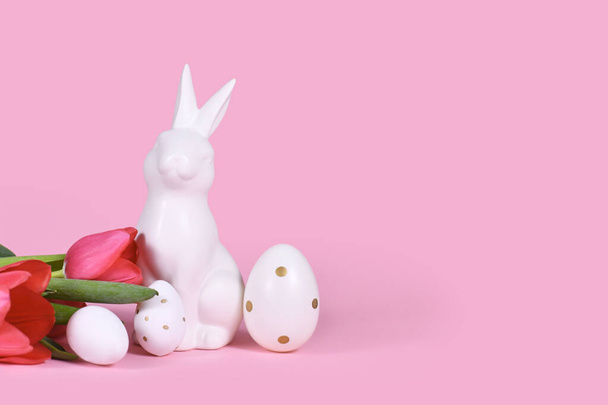 Easter bunny, white eggs with golden dots and tulip spring flowers on pink background with copy space - Foto, afbeelding