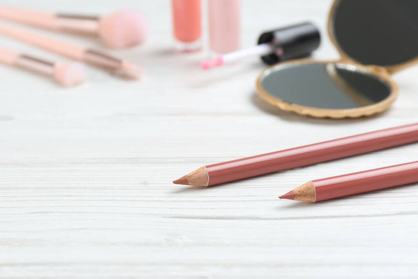 Lip pencils and other makeup products on white wooden table, space for text - Fotó, kép