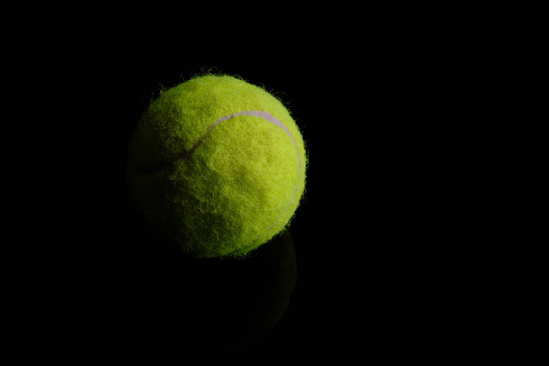 Green tennis ball at black background - Foto, afbeelding