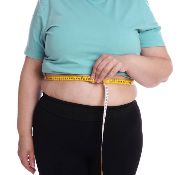 Overweight woman measuring waist with tape on white background, closeup - Foto, afbeelding