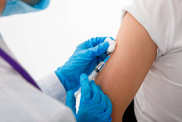 Médecin tenant la seringue avant de faire l'injection au patient sous masque médical. Vaccin Covid-19 ou coronavirus. gros plan - Photo, image