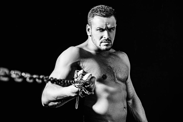 Strong man with perfect body posing naked. Shirtless bodybuilder standing with chain. Break concept. - Фото, зображення