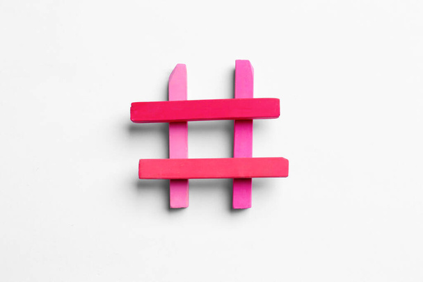 Hashtag symbol of pink chalk pieces on white background, top view - Фото, зображення