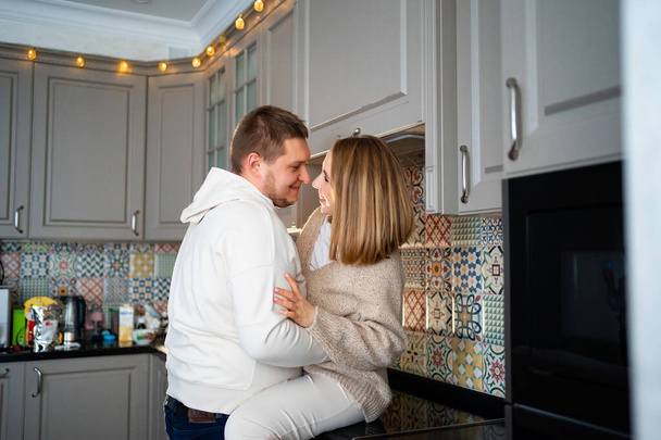 a happy and loving couple fooling around and hugging at home in the kitchen  - Photo, image