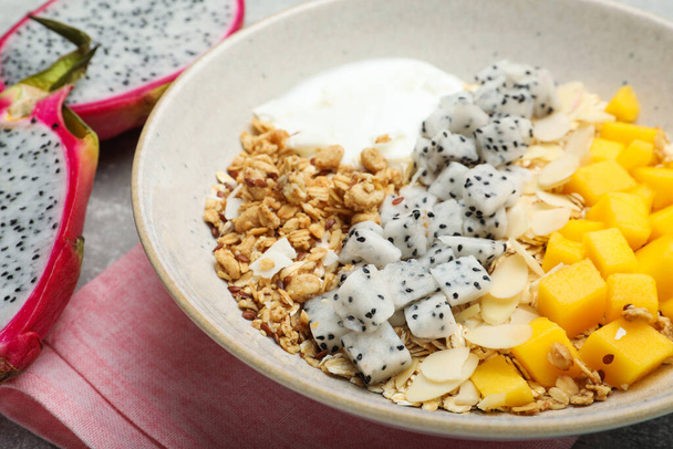 Bowl of granola with pitahaya, mango and yogurt on table, closeup - Фото, зображення