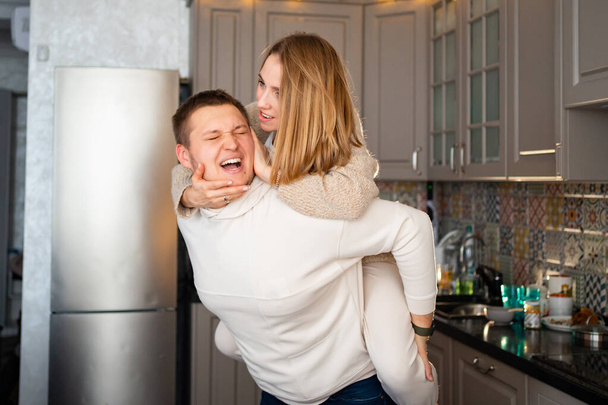 a happy and loving couple fooling around and hugging at home in the kitchen  - Фото, зображення
