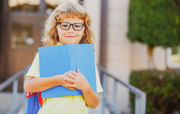 Excited schoolboy with book at the school. - Фото, изображение