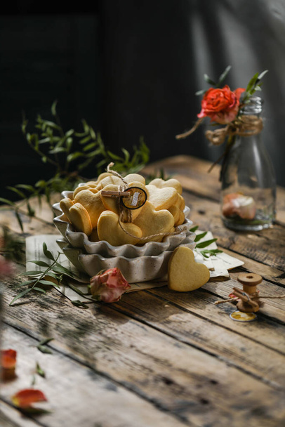 Домашнее печёное печенье ручной работы с розами на деревянной доске в стиле деревенского минимализма - Фото, изображение