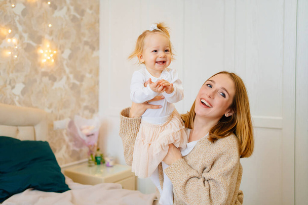 Cute mom and baby daughter lie down, play and hug in bed. games with children.  - Foto, Bild
