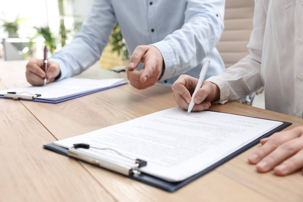 Businesspeople signing contract at table in office, closeup - Фото, изображение