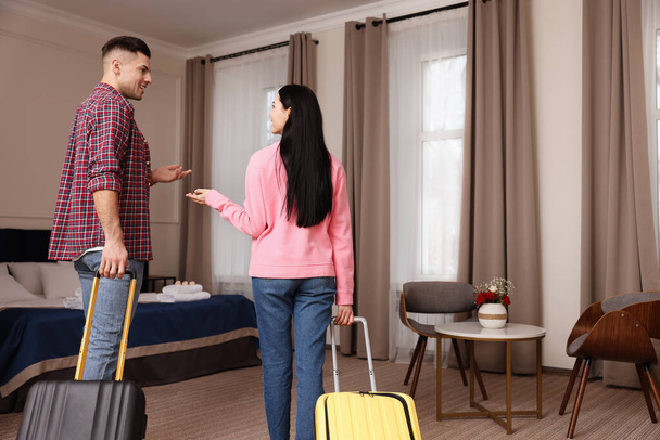 Happy couple with suitcases walking into hotel room - Foto, imagen