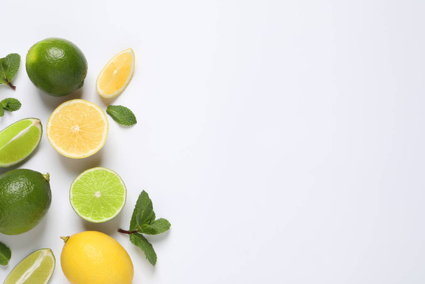 Fresh ripe lemons, limes and mint leaves on white background, top view - Fotó, kép
