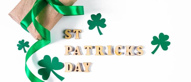 Shamrock and gift with green ribbon on white background. Good luck symbols for St. Patrick's Day. Irish holiday. Banner format. - Photo, Image