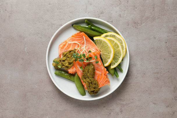 Tasty cooked salmon with pesto sauce on grey table, top view - Fotografie, Obrázek